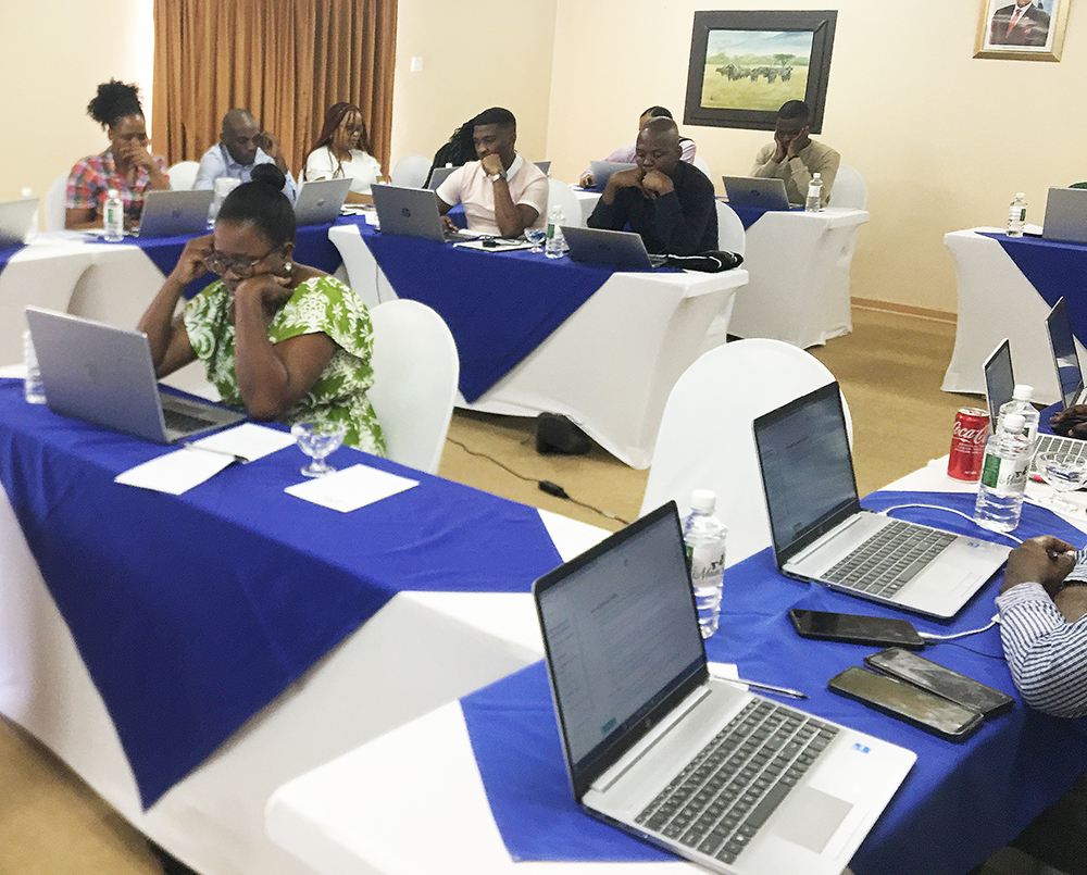 Learners work on their laptop computers in a conference room.